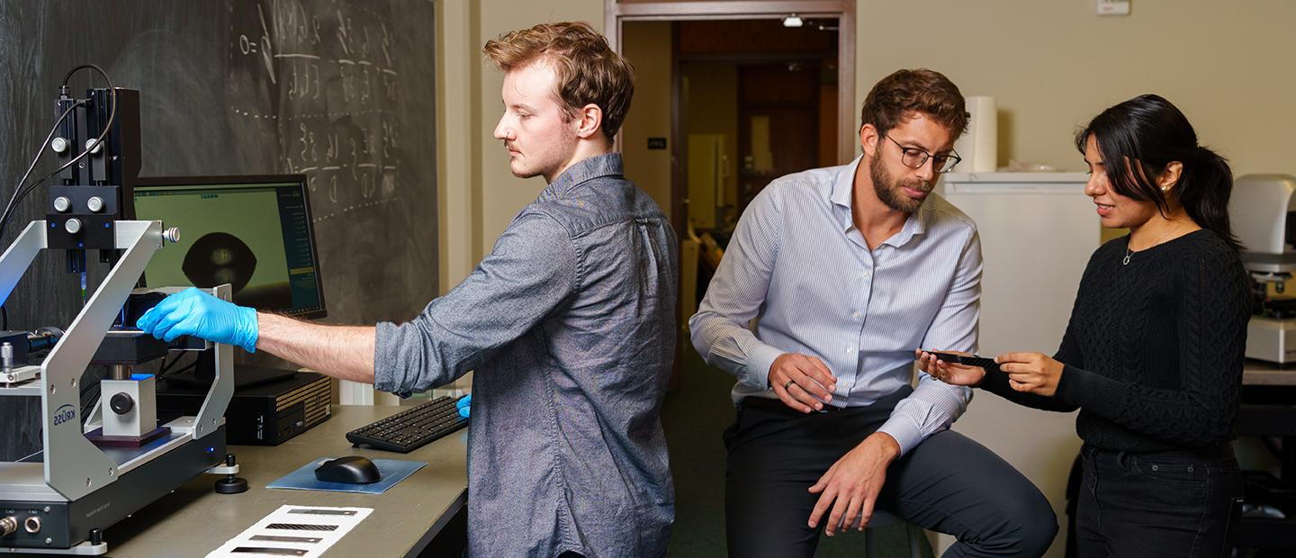 Three people working with equipment in a mechanical lab